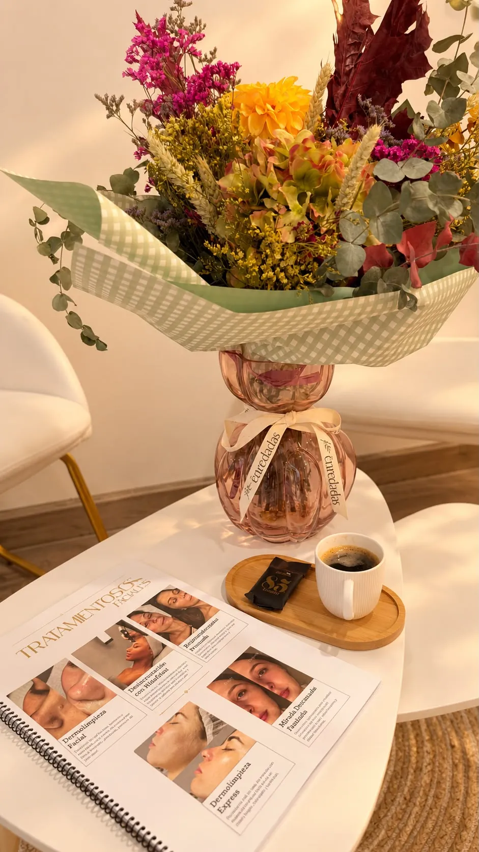 Recepción del centro: ramo de flores, café y el dossier de tratamientos faciales sobre la mesa